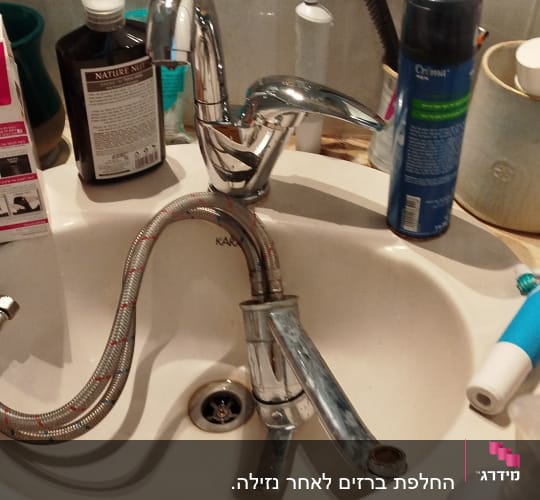 כיור עם ברז וכלים שונים בחדר אמבטיה